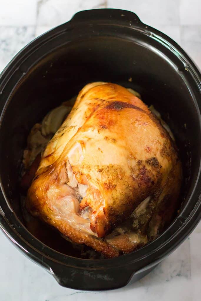 overhead shot of a bone-in turkey breast in a slow cooker.