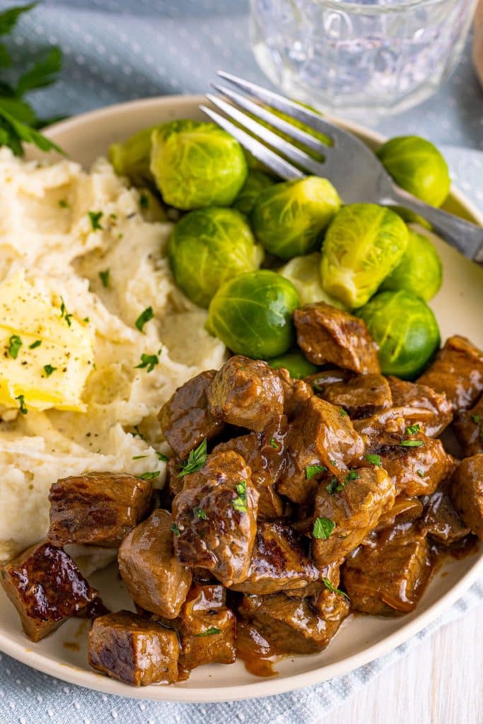 plates of steak bites, mashed potatoes, and brussels sprouts.
