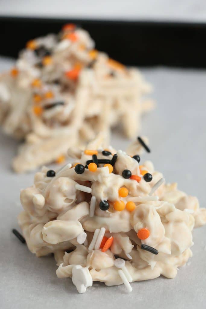 white chocolate haystacks on wax paper with halloween sprinkles.