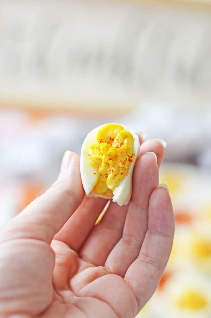 hand holding a deviled egg with a bite missing.