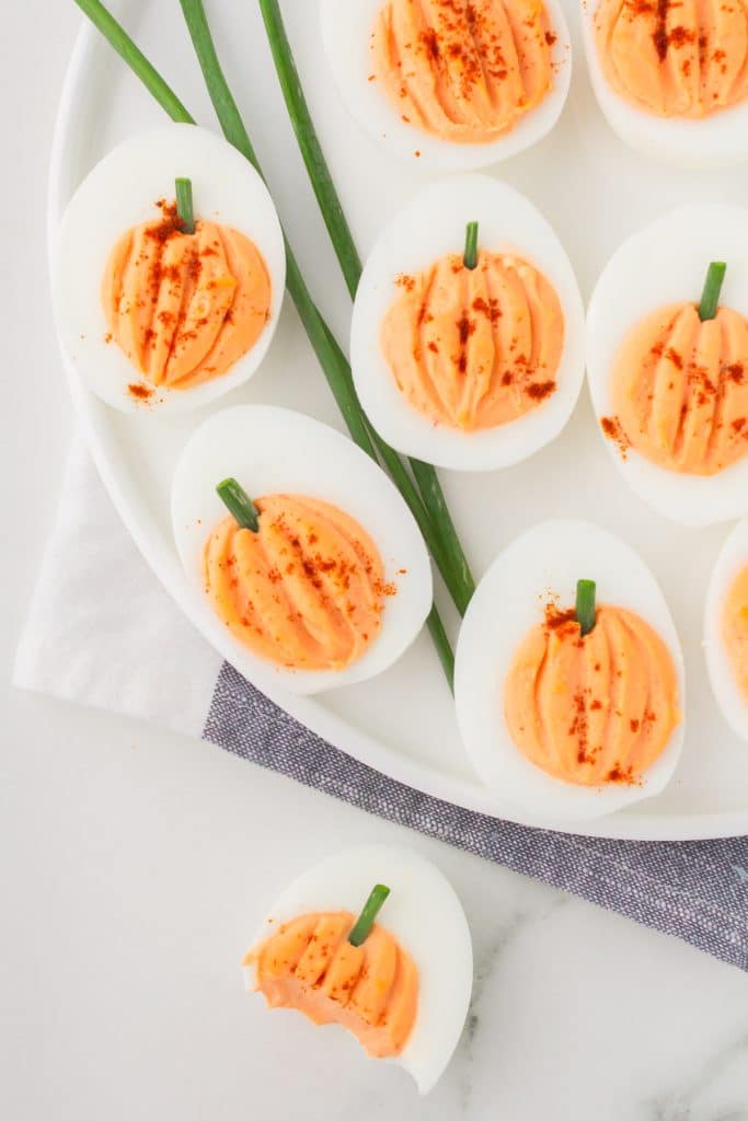 overhead shot of pumpkin deviled eggs, one with a bite missing.