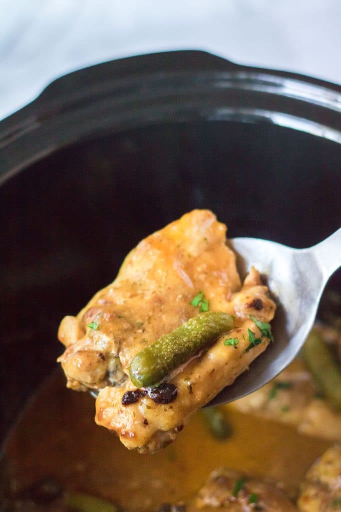 chicken and a pickle being lifted from a crockpot.