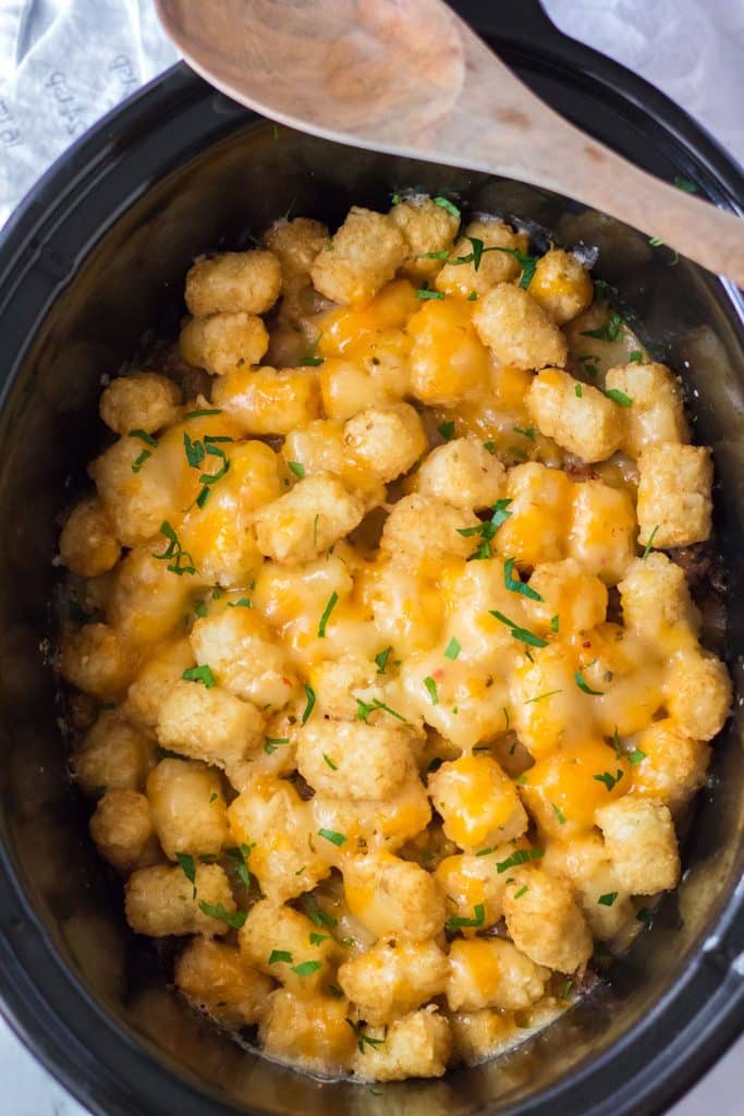 overhead shot of cheesy tater tot casserole in a slow cooker.