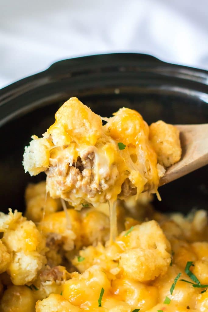 wooden spoon lifting tater tot bake from a crockpot.