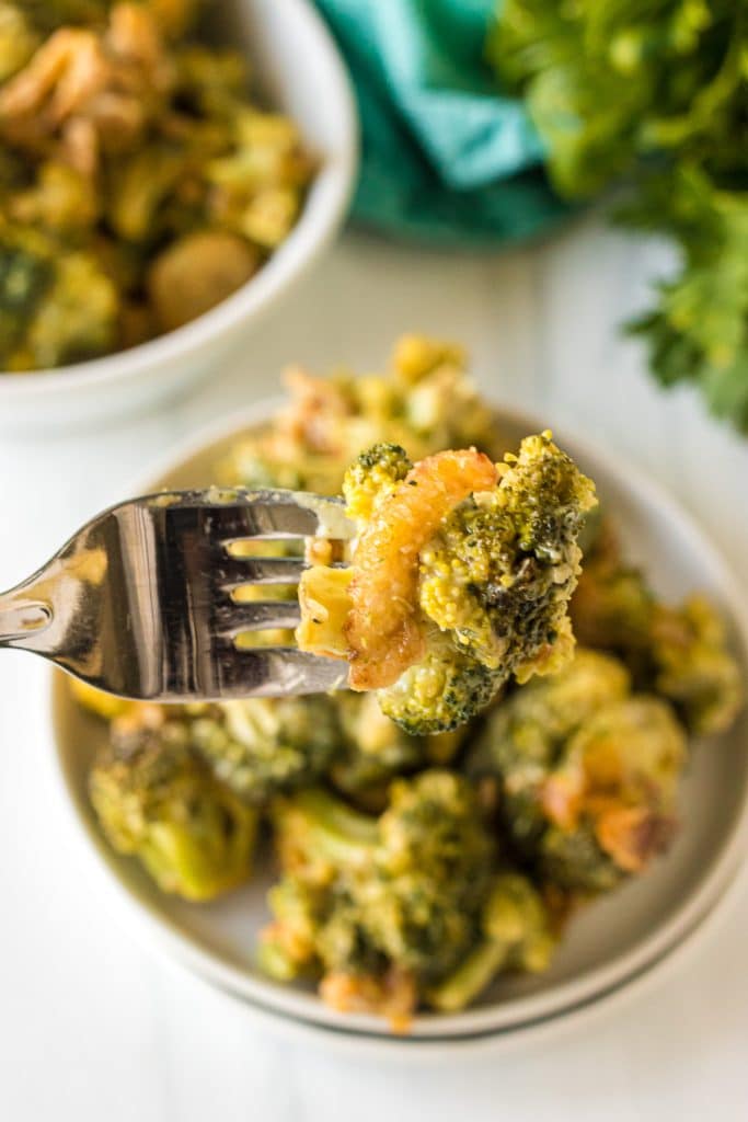 a fork lifting a bite of broccoli casserole from a plate.