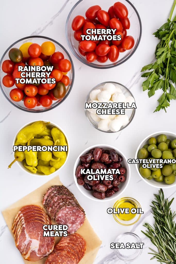 overhead shot of labeled ingredients laid out to make an antipasto platter.