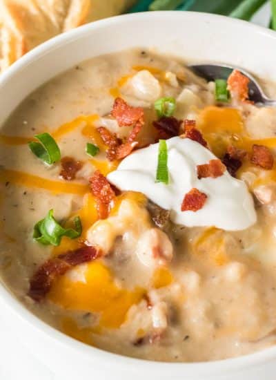 bowl of potato soup topped with bacon, sour cream, chives, and cheese.