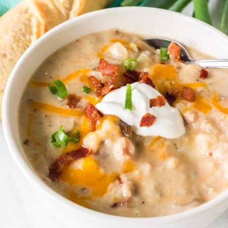 bowl of potato soup topped with bacon, sour cream, chives, and cheese.