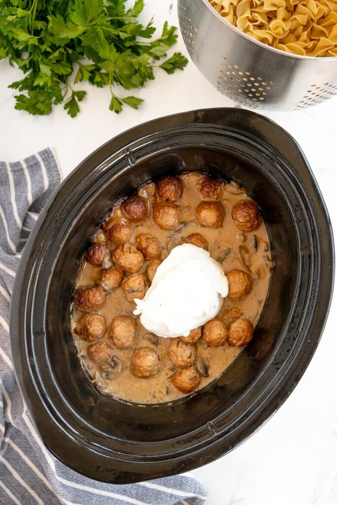 sour cream in a crockpot with meatballs.