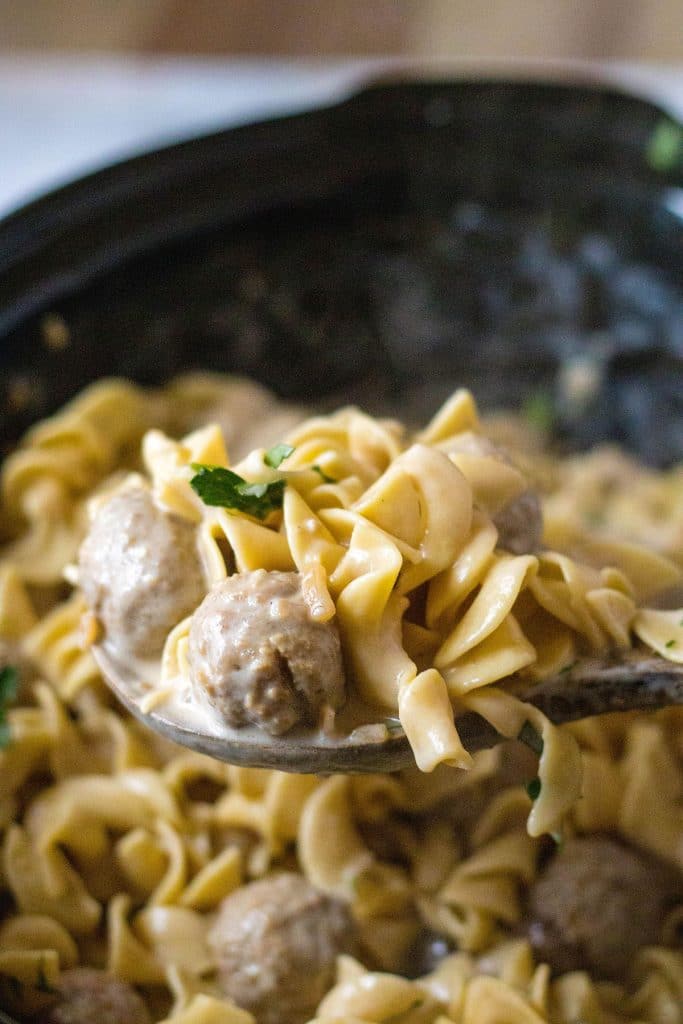 spoon scooping meatball stroganoff from a slow cooker.