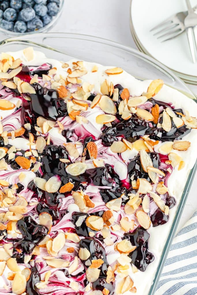 overhead shot of a baking dish filled with blueberry heaven on earth dessert topped with slivered almonds.