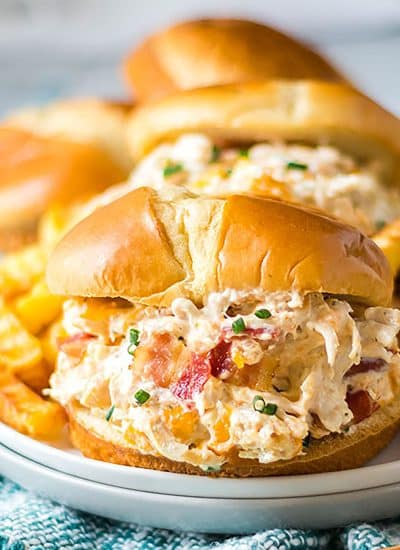 slow cooker chicken bacon ranch sandwiches on a white plate with fries.