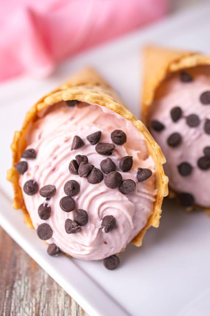 closeup of a strawberry cheesecake cannoli cone with mini chocolate chips.