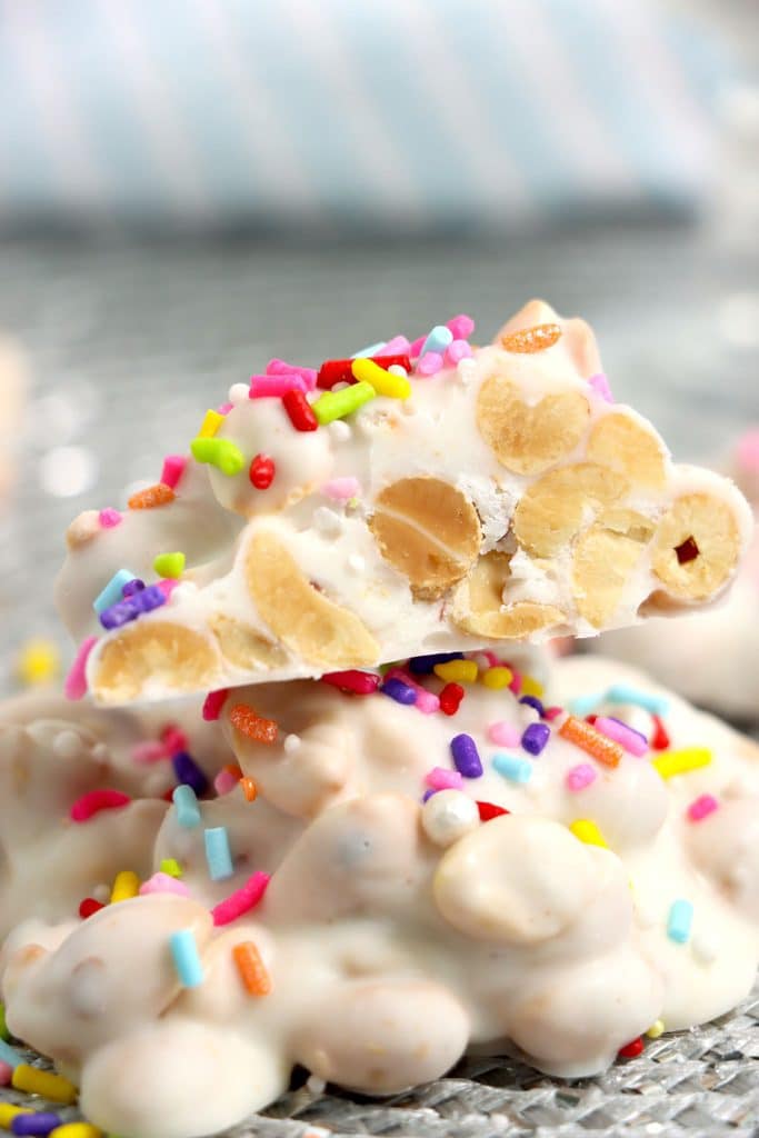 white chocolate peanut cluster stack with rainbow sprinkles.
