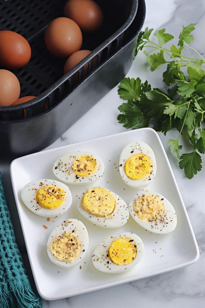 plate of sliced hard boiled eggs next to an air fryer.