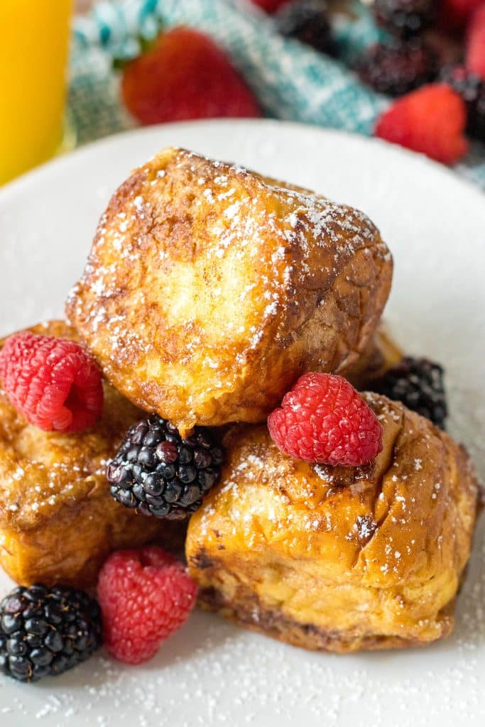 stack of 3 hawaiian roll french toasts topped with berries.