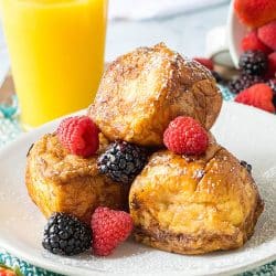 hawaiian roll french toast with blackberries, raspberries, and powdered sugar.
