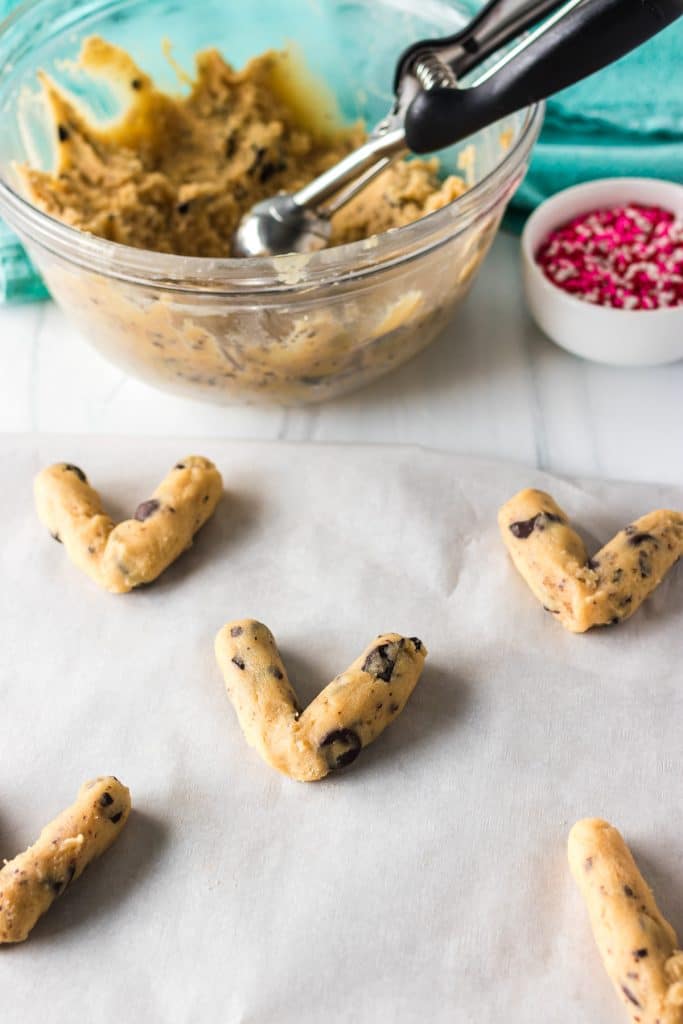 cookie dough in the shape of "Vs" on a parchment lined baking sheet.