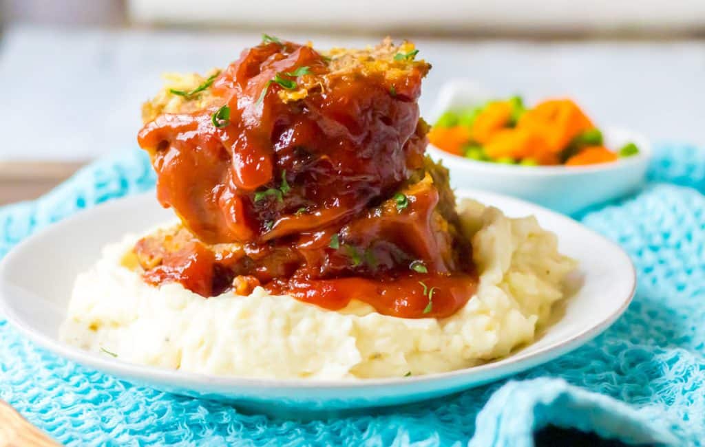 slices of meatloaf on top of mashed potatoes.