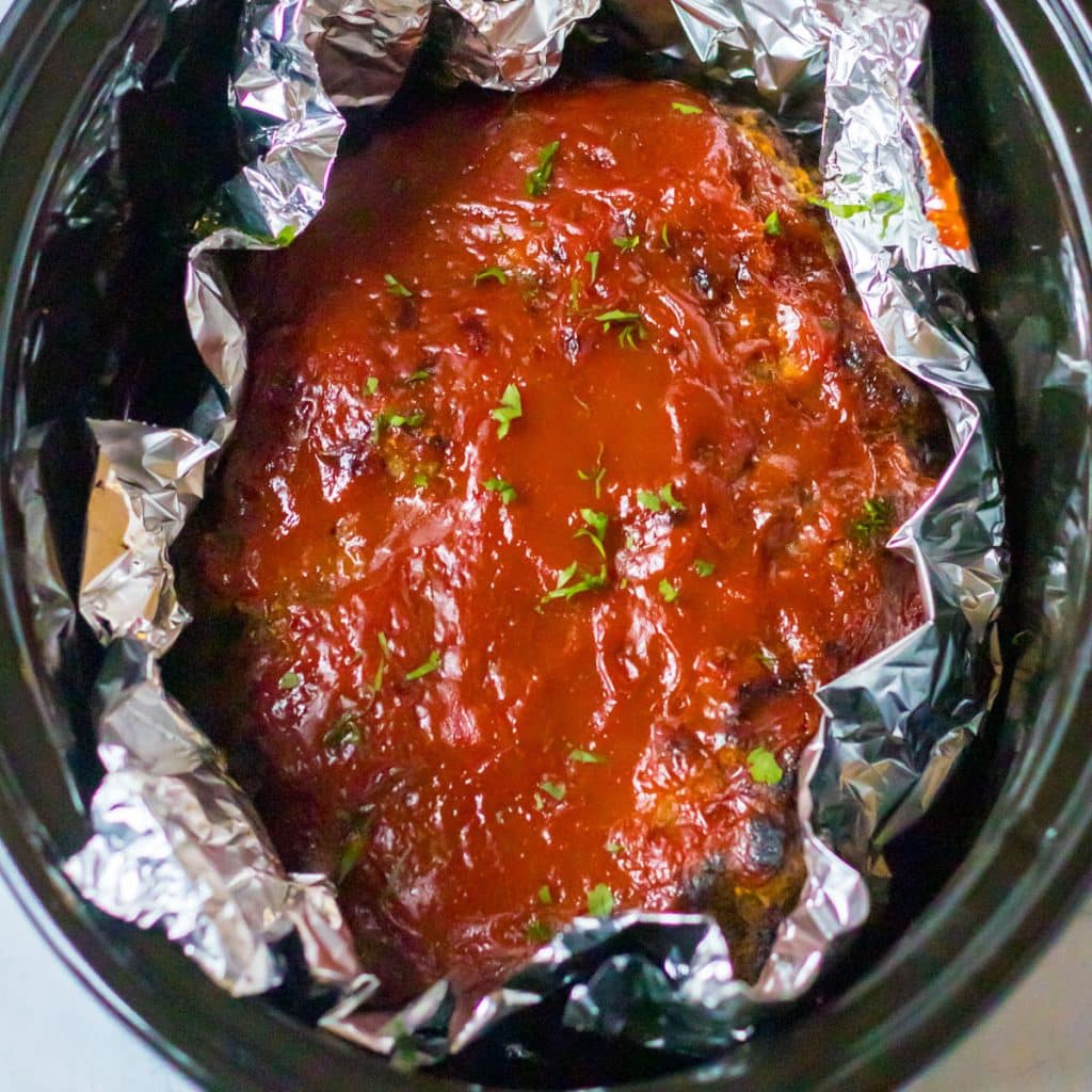 overhead shot of bbq sauce glazed meatloaf in a slow cooker.
