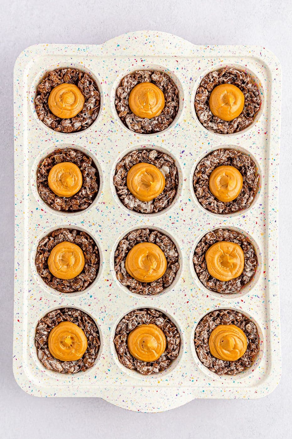 overhead shot of peanut butter filling in bird nest cookies in a cupcake pan.