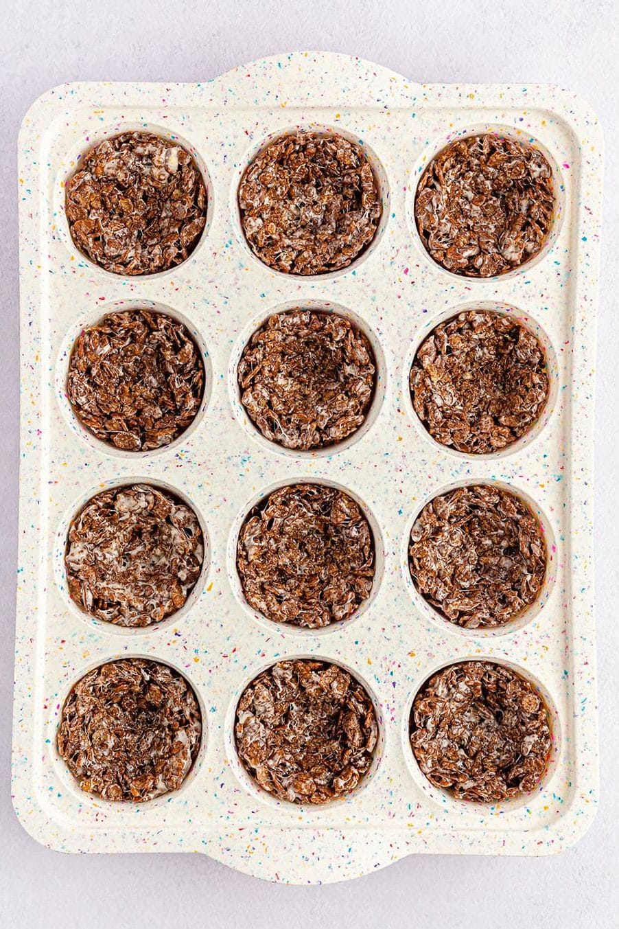 overhead shot of cocoa pebbles birds nests in a cupcake pan.