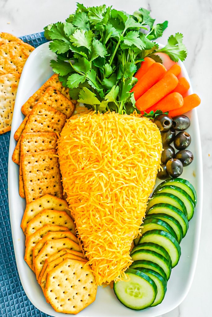 easter cheese ball shaped like a carrot on a platter with veggies and crackers.