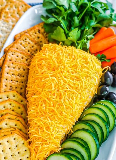 carrot shaped cheese ball on a platter with veggies and crackers.