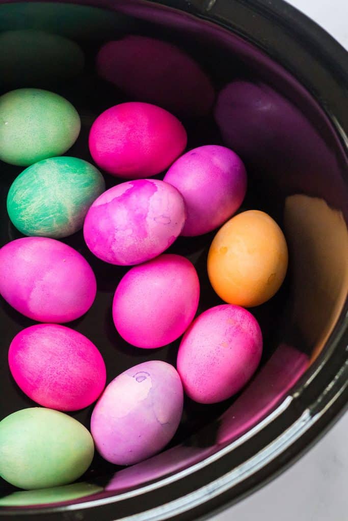 overhead shot of vibrantly colored easter eggs in a slow cooker.