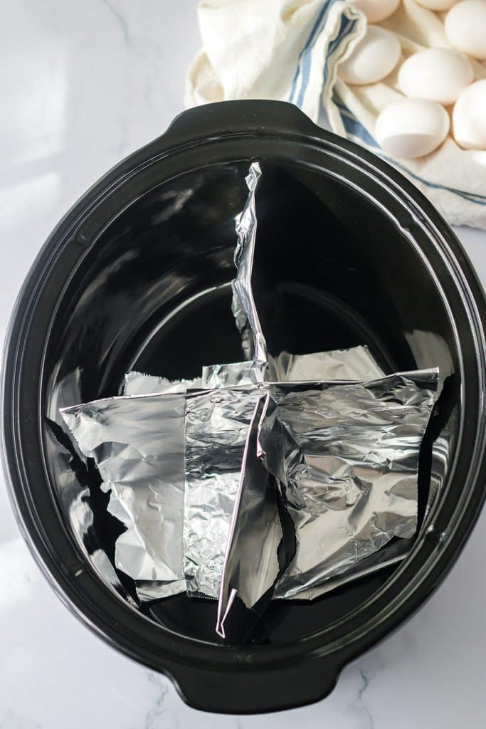 overhead shot of a slow cooker divided into 4 sections with tin foil.