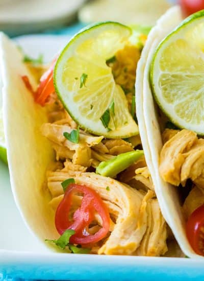 side view of two honey lime chicken tacos on a plate.