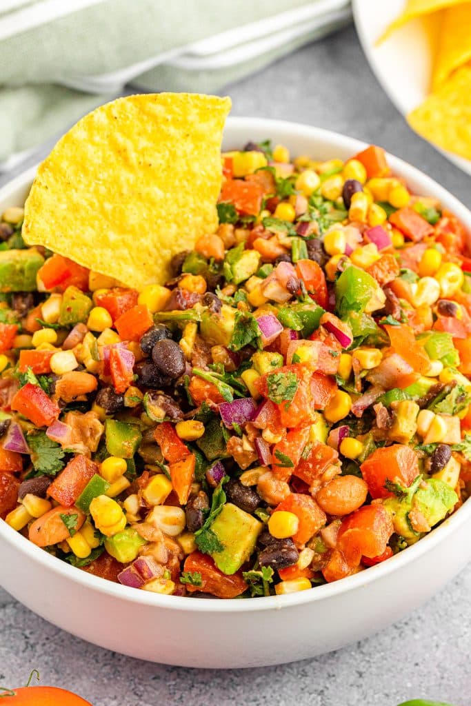 bowl of cowboy caviar dip with a tortilla chip stuck in it.