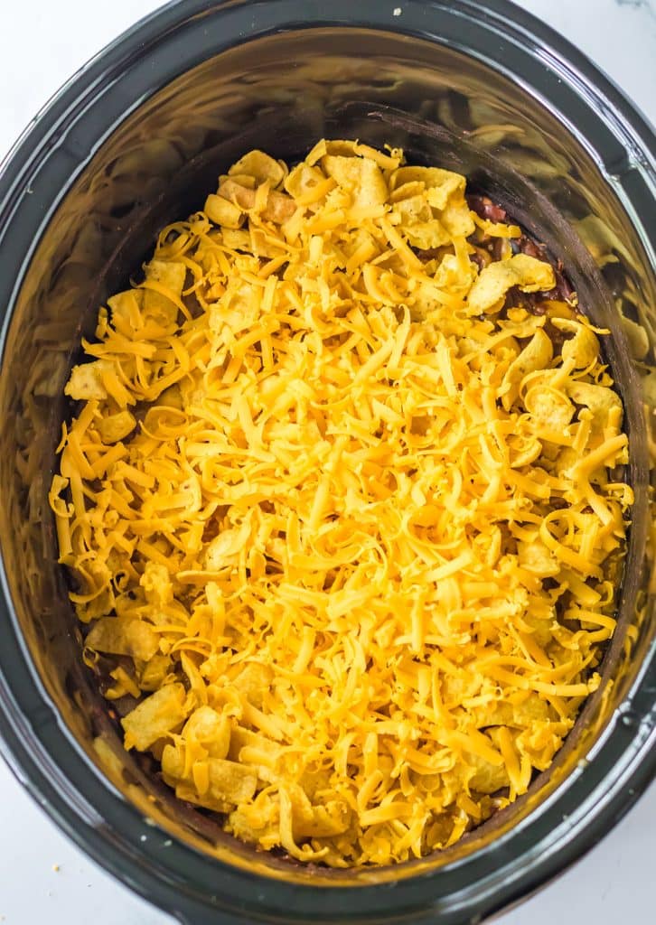 cheddar cheese sprinkled on chili in a crockpot.