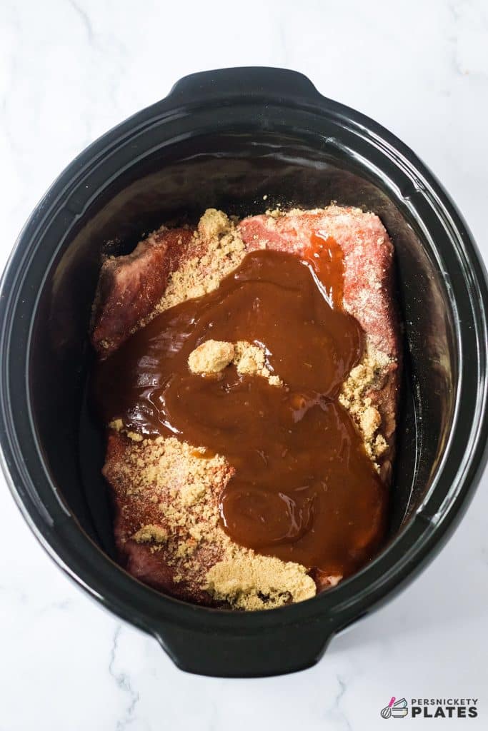 overhead shot of a brisket and sauce in a slow cooker.