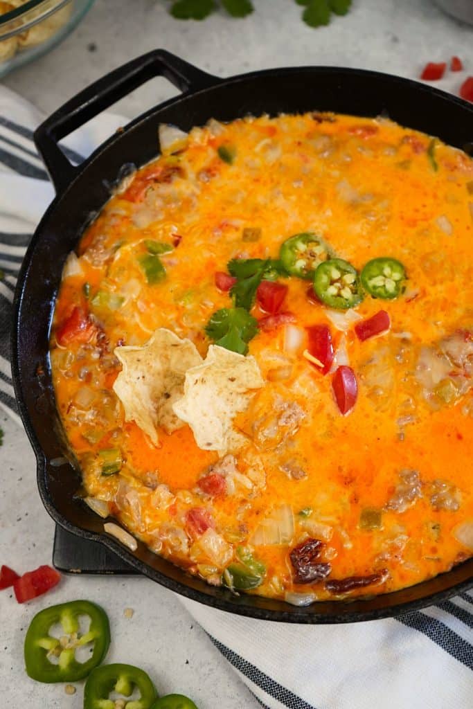 smoked queso in a skillet topped with jalapenos & tomatoes.