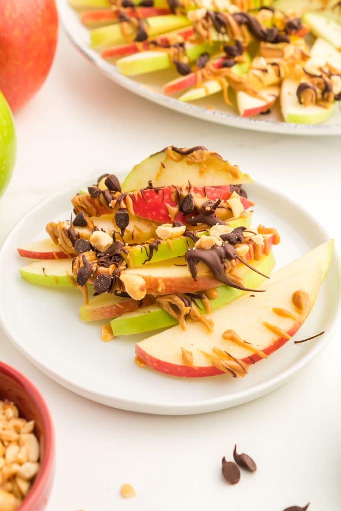 white plate with a pile of peanut butter apple nachos.