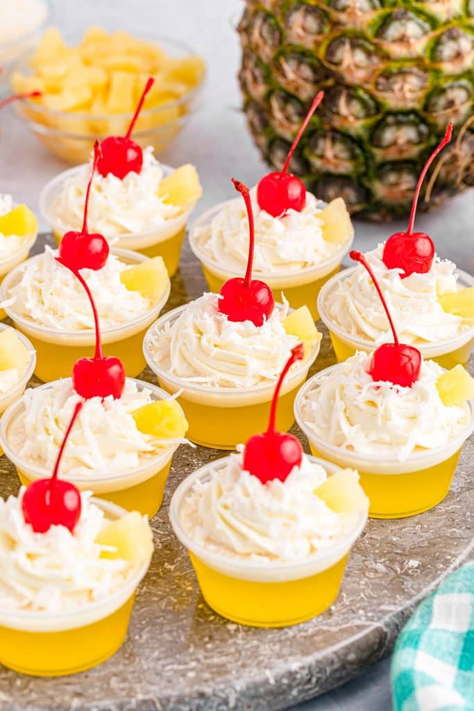 Platter of pina colada jello shots topped with cherries.