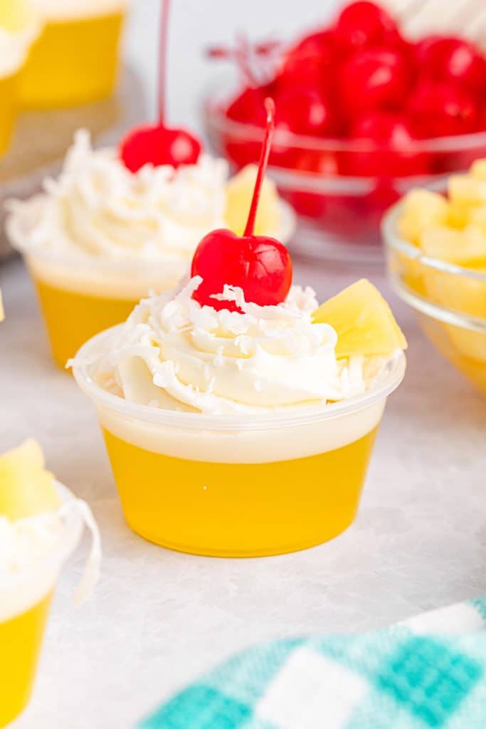jello shot cup topped with whipped cream, coconut, and cherry.