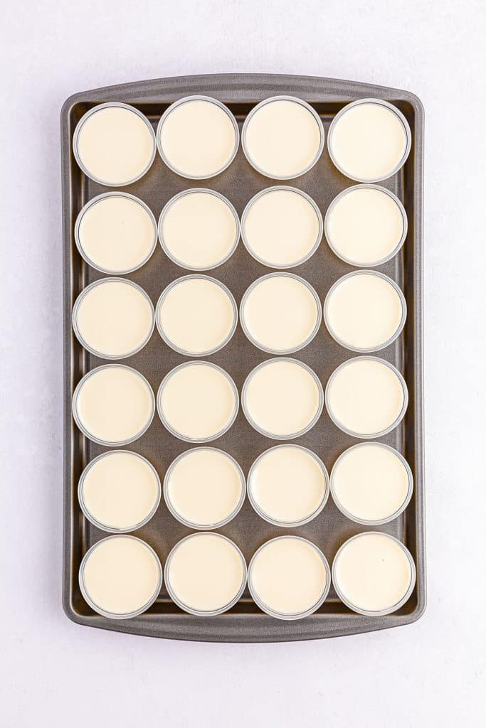 overhead shot of white jello shot cups on a cookie sheet.