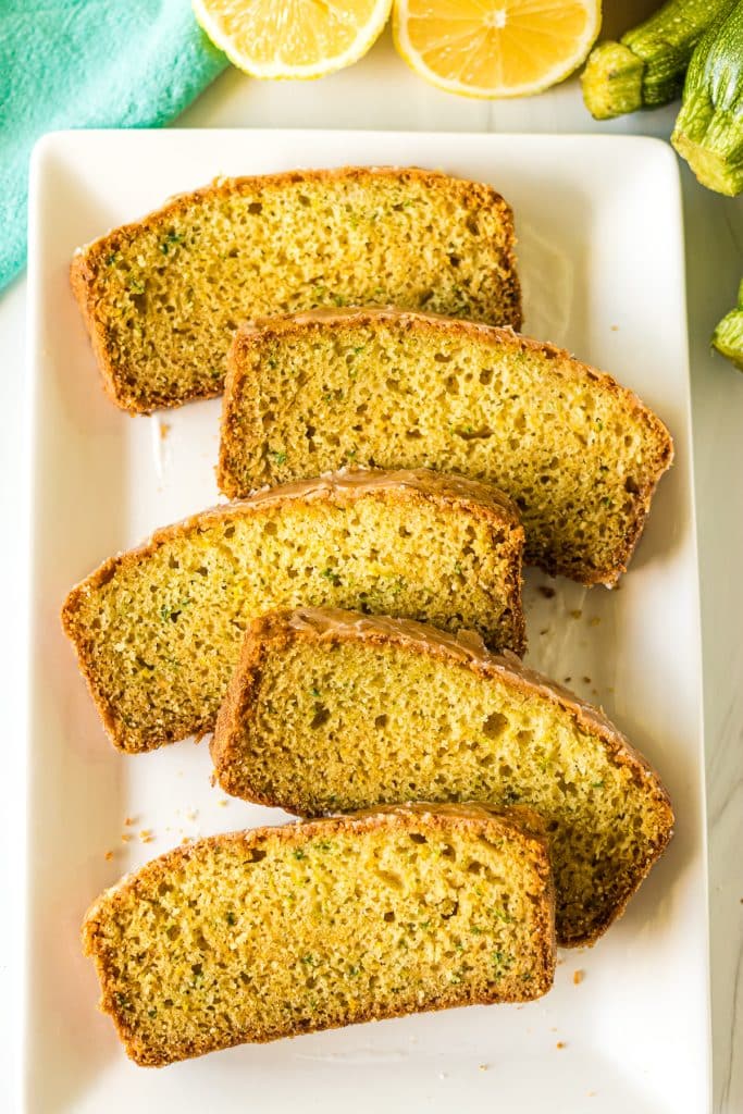 staggered slices of lemon zucchini bread laid out on a white platter.