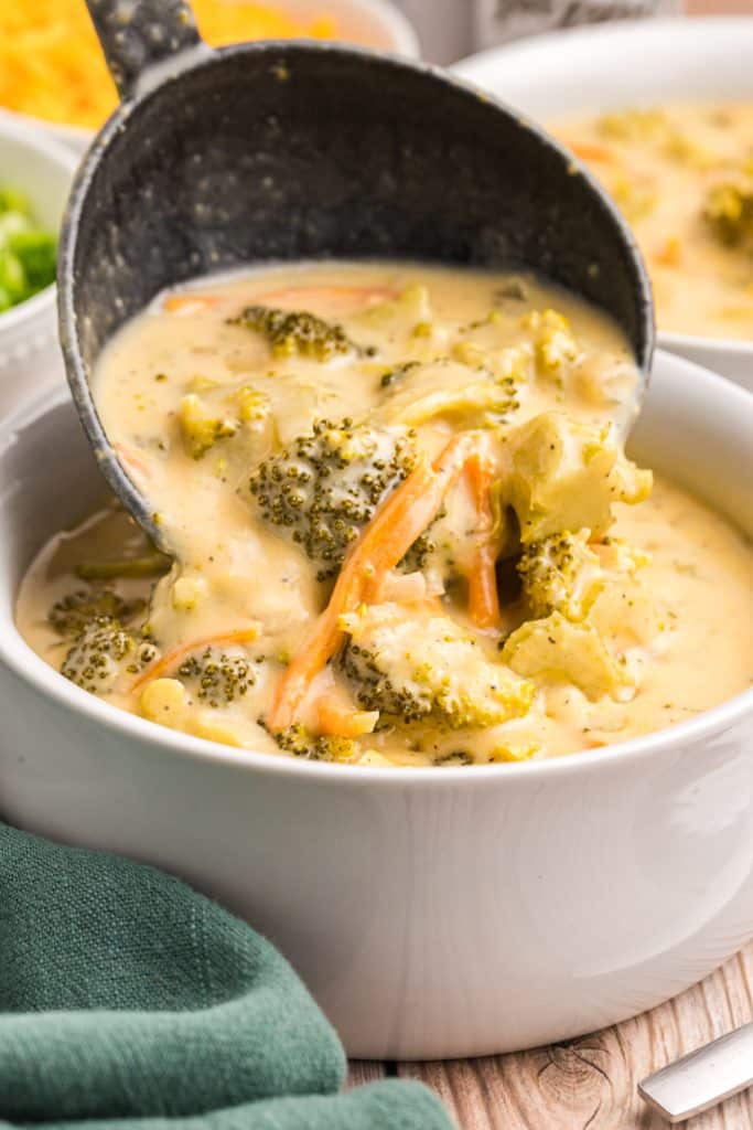 ladle pouring broccoli cheddar soup into a bowl.