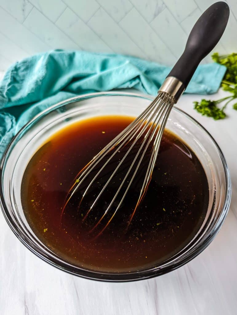glass bowl of sauce with a whisk in it.
