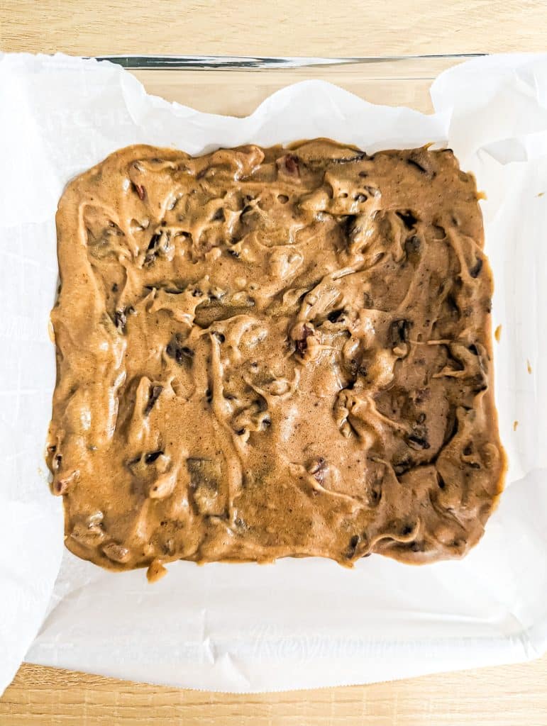 overhead shot of cookie dough in a baking dish with parchment paper.
