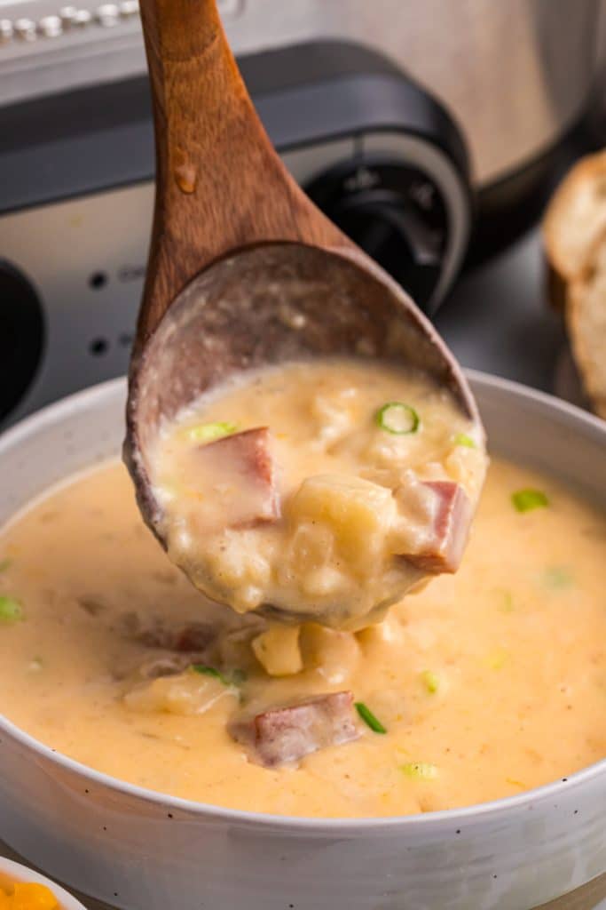 ladle scooping ham & potato soup into a bowl.
