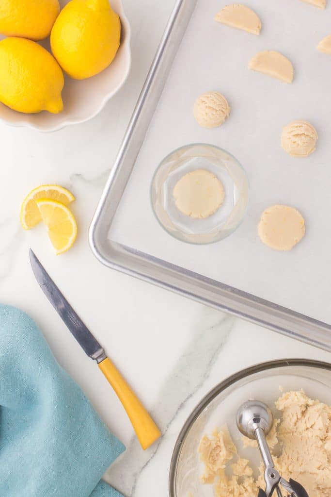overhead shot of lemons and cookie dough on a baking sheet.