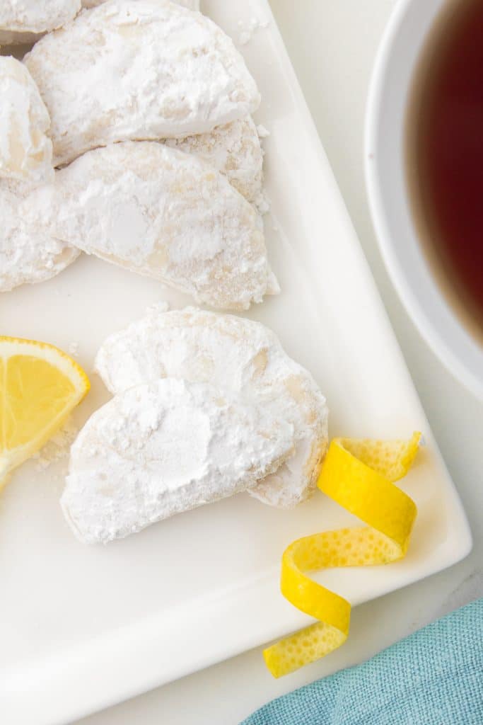 overhead shot of lemon powder sugar cookies next to a cup of tea.