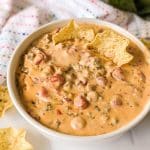 bowl of sausage cheese dip with tortilla chips dipped in.