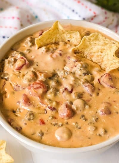 bowl of sausage cheese dip with tortilla chips dipped in.