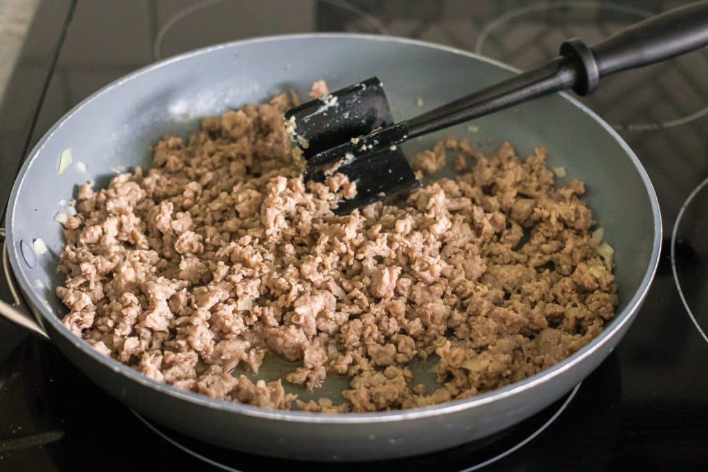 meat chopper in a pan with ground sausage.