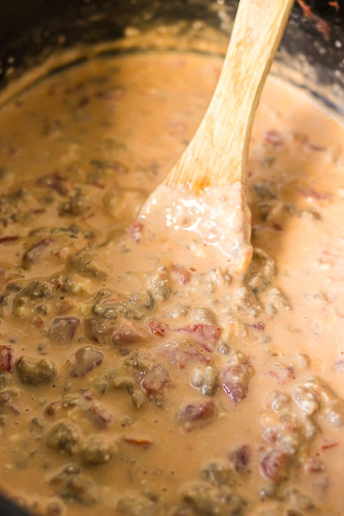 wooden spoon in a crockpot of sausage cheese dip.